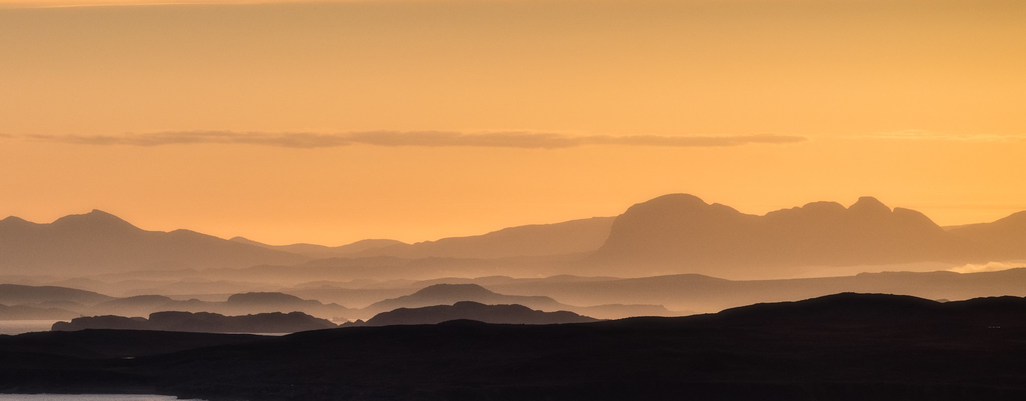 glowing orange sky after sunset with distant hills silhoutted
